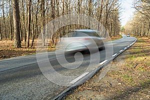 A car driving fast on an asphalt road through the forest