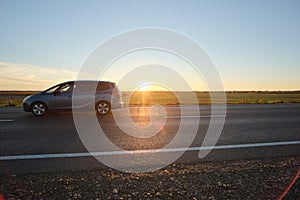 Car driving fast on intercity road at sunset. Highway traffic in evening