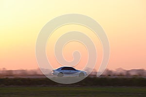 Car driving fast on intercity road at sunset. Highway traffic in evening