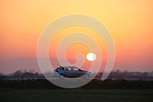 Car driving fast on intercity road at sunset. Highway traffic in evening