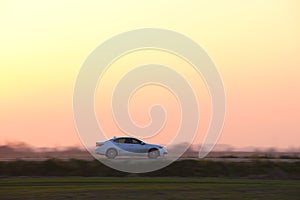 Car driving fast on intercity road at sunset. Highway traffic in evening