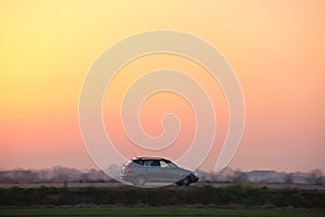 Car driving fast on intercity road at sunset. Highway traffic in evening