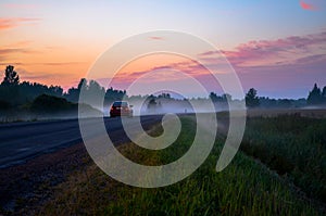 Car driving into the forest fog at sunset