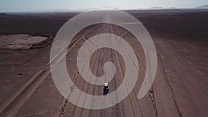 Car driving on gravel road in aerial desert. Sandy landscape, nobody in Namibia.