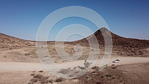 Car driving on gravel road in aerial desert. Sandy landscape, nobody in Namibia.