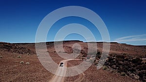 Car driving on gravel road in aerial desert. Sandy landscape, nobody in Namibia.