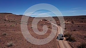 Car driving on gravel road in aerial desert. Sandy landscape, nobody in Namibia.