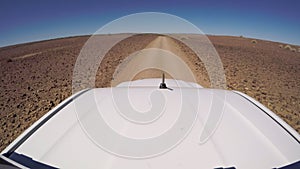Car driving on gravel road in desert. Sandy landscape, nobody in Namibia.