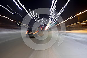 The car is driving at high speed on the night street of the city, blurred image along the lines of the road with zoom