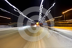 The car is driving at high speed on the night street of the city, blurred image along the lines of the road with zoom