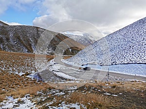 A car driving on an ice covered road at Lindis Pass in New Zealand in winter afternoon