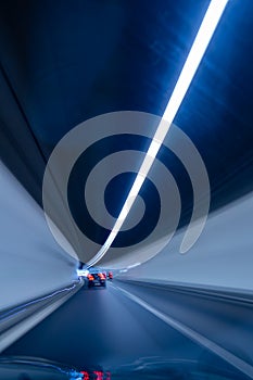 Car driving through an illuminated tunnel. Blurry long exposure of traffic. Inside point of view, no people