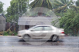 Car driving motion through gale rain on front wooden house