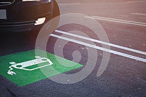 car driving in parking lot with symbol of a car with cable plug painted in green and white on ground