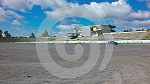 Car driving on race circle on abandoned autodrome with blue sky background