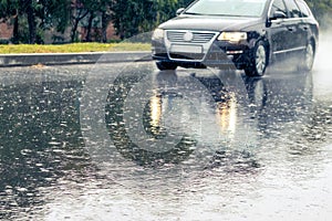 The car is driving on the road during heavy rain. Summer rain on the track