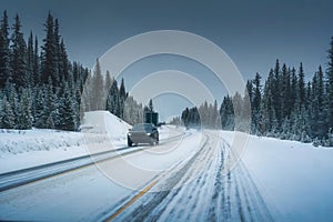 Car driving on the road through snowy pine forest and blizzard in national park on cloudy winter day