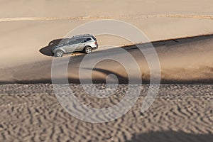 Car driving through sand dune