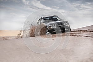 Car driving through sand dune