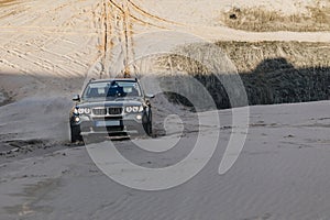 Car driving through sand dune