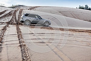 Car driving through sand dune