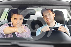 Car driving school instructor teaching male driver