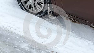 Car is driving on slippery snow-covered road in forest area. POV close-up of wheel in skid. Winter Driving Hazard