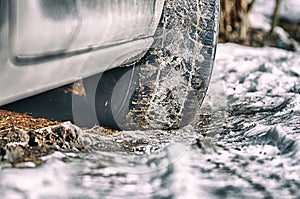 Car while driving on snow, closeup on the tire.