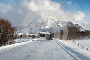 Car driving on snow covered road with mountain in countryside