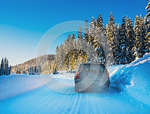 Car driving on a snow covered road in a wilderness forest