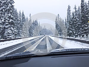 Car driving on snow-covered snowy mountain road in winter snow. Driver`s point of view viewpoint looking through windshield.