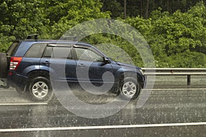 The car is driving on a wet road. Slippery road after rain. Splashes from under the wheels of transport. Rain on the highway