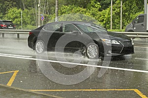 The car is driving on a wet road. Slippery road after rain. Splashes from under the wheels of transport. Rain on the highway