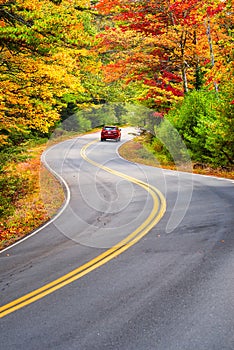 Car driving through winding road in New England autumn