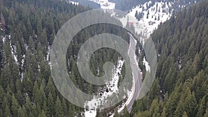 Car driving on winter country road in snowy forest, aerial view from drone in 4k. aerial view of the forest with tall