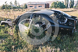 Car dump, scrap metal. Close-up of an old abandoned car in a junkyard with grass sprouting inside and overgrown cobwebs