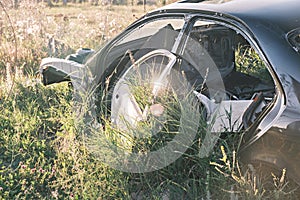 Car dump, scrap metal. Close-up of an old abandoned car in a junkyard with grass sprouting inside and overgrown cobwebs