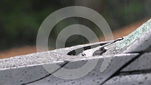 Car engine hood and car windshield wiper on rainy day with heavy rainfall and thunderstorm shows dangerous weather for aquaplaning