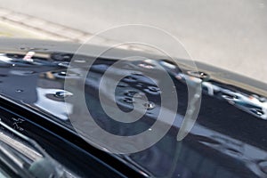 Car engine hood with many hail damage dents show the forces of nature and the importance of car insurance and a replacement value