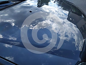 Car engine hood with many hail damage dents show the forces of nature and the importance of car insurance and a replacement value