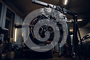 Car engine suspended on a hydraulic hoist in the workshop