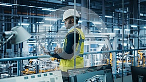 Car Factory: Professional Male Automotive Engineer Wearing Hard Hat, Walking, Using Laptop