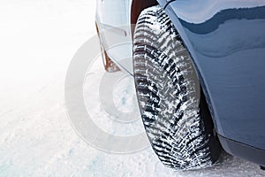 Car fitted with snow tyre on a winter road