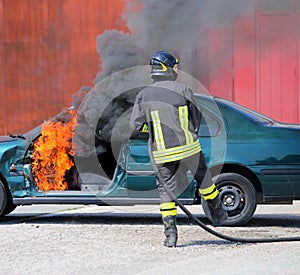 Car with flames and black smoke firefighter intervening to tampe