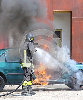 Car with flames and black smoke firefighter intervening to tampe