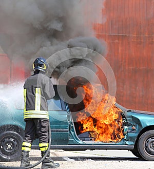 Car with flames and black smoke firefighter intervening to tampe