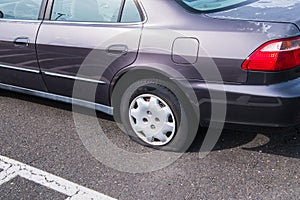 Car with a flat tire on an asphalt parking lot