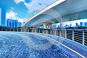 Car-free asphalt road and city buildings under sunset.