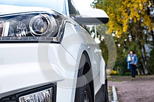 Car front view close-up on the background of a Park alley. Headlight glass. Background design. Detail of modern car headlights