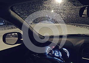 Car with frozen windshield stopped on roadside in the night snowfall